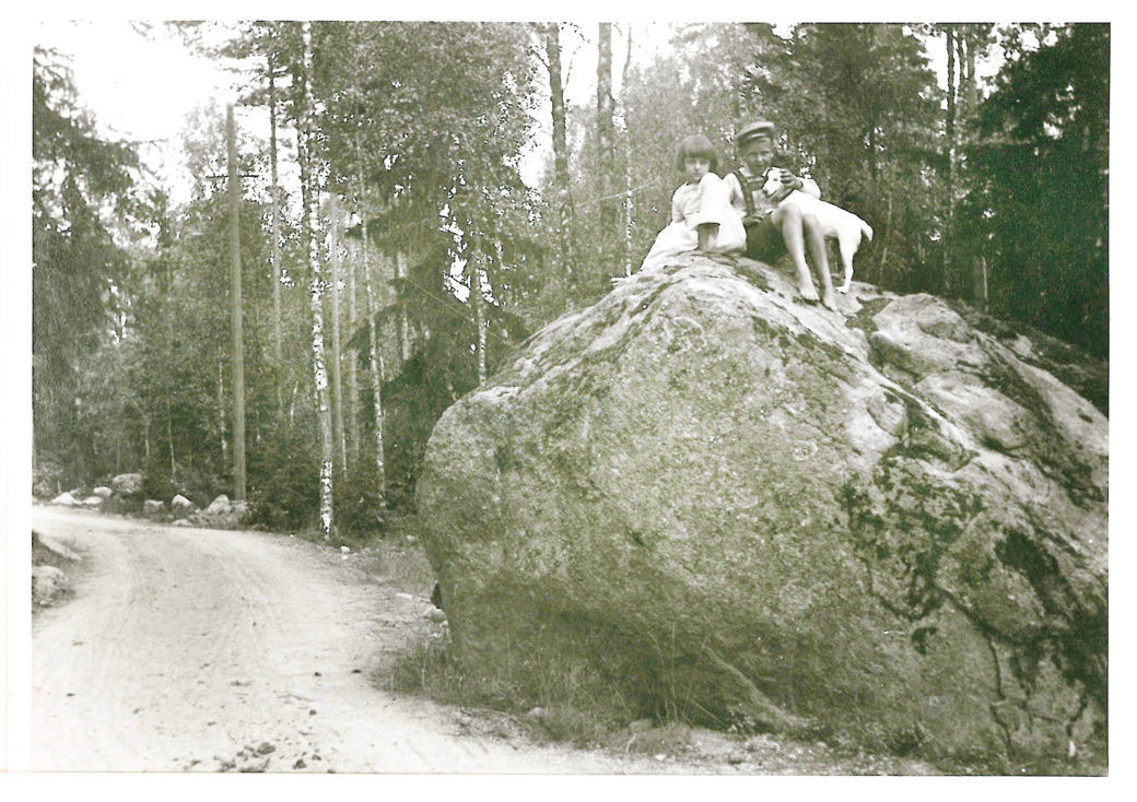 Lapsia kivellä Träskändan tien varrella 1910-luvulla. Kiven pitäisi olla edelleen samalla paikalla nykyisen Asematie 27:n kohdalla urheilukentän pohjoispuolella. Barn på sten invid Träskända vägen på 1910-talet. Stenen torde finnas kvar vid nuvarande Stationsvägen 27 norrom sportplanen.